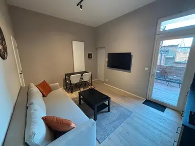 a living room with a white couch and a tv at Apartment central Lier in Lier