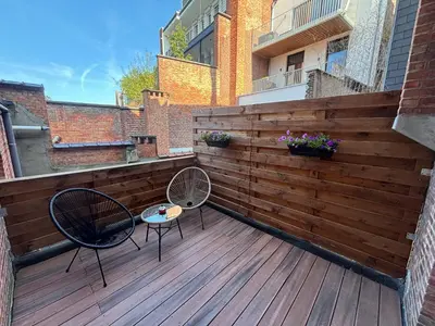 a wooden deck with two chairs and a table at Apartment central Lier in Lier
