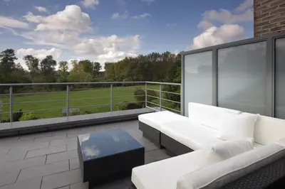 a balcony with a white couch and a table at Aan Den Oever Logies in Korbeek-Dijle