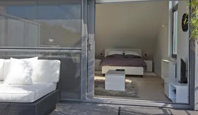 a bedroom with a bed and a white couch at Aan Den Oever Logies in Korbeek-Dijle
