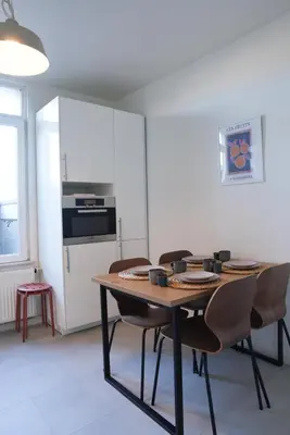 a kitchen with a table with chairs and a refrigerator at Antwerp Parkside apartments in Antwerp