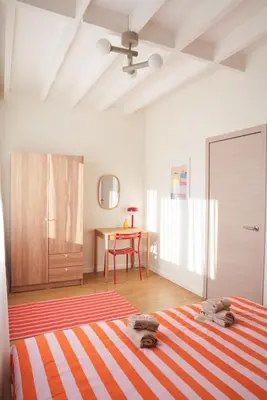a bedroom with an orange and white striped bed and a table at Antwerp Parkside apartments in Antwerp