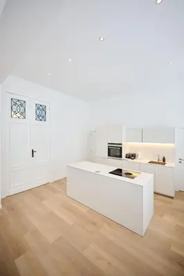 a white kitchen with white counters and a wooden floor at Louise City 2 in Brussels