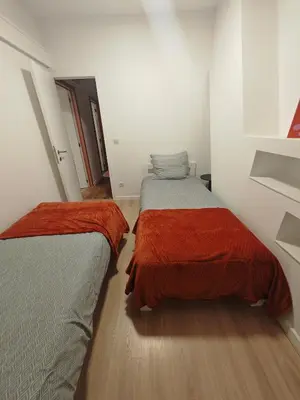 two beds in a room with white walls and wood floors at The Nest in Antwerp