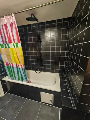 a bath tub in a bathroom with black tiles at The Nest in Antwerp
