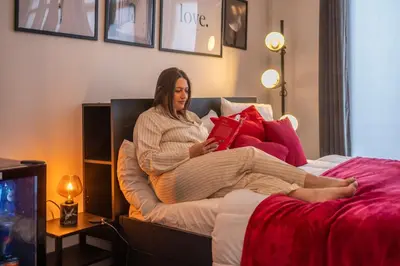 a woman sitting on a bed reading a book at Euro Edens Cosy Historic Home in Brussels Jacuzzi, Garden, Central Location in Brussels