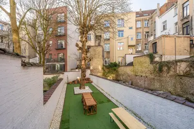 a courtyard with benches and a tree and buildings at Euro Edens Cosy Historic Home in Brussels Jacuzzi, Garden, Central Location in Brussels