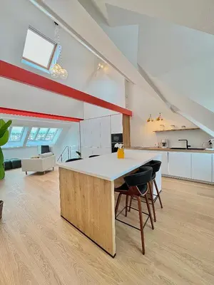 an attic kitchen with a large white table and chairs at Duplex Design & Élégant au Coeur de Bruxelles in Brussels