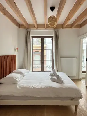 a bedroom with a bed and a large window at Duplex Design & Élégant au Coeur de Bruxelles in Brussels