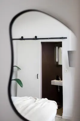 a mirror reflecting a bedroom with a bed and a sink at ROMY ANTWERP Sint-Jansvliet in Antwerp