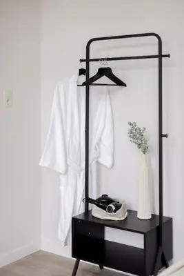 a black rack with a white shirt hanging on a wall at ROMY ANTWERP Sint-Jansvliet in Antwerp