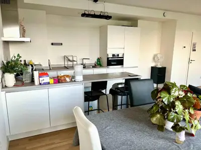 a kitchen with white cabinets and a table with chairs at Elegant Apartment Near Atomium Ideal for Families in Brussels