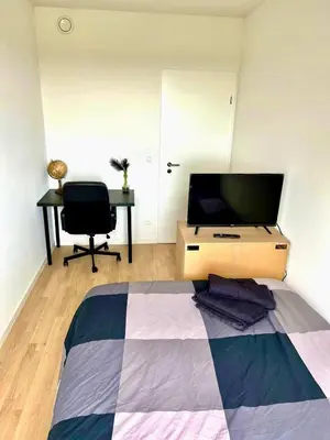 a bedroom with a tv and a desk and a bed at Elegant Apartment Near Atomium Ideal for Families in Brussels