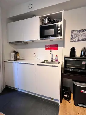 a kitchen with white cabinets and a sink and a microwave at Lovely Studio with Balcony by Grand Place for 4 in Brussels