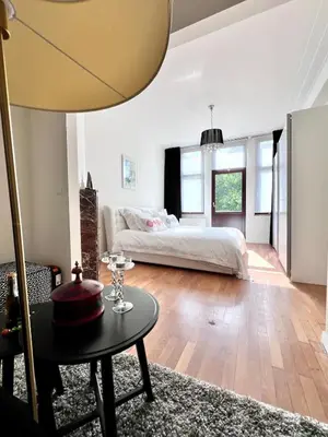 a bedroom with a bed and a table in a room at Chic Studio Heart of the City with Balcony in Brussels