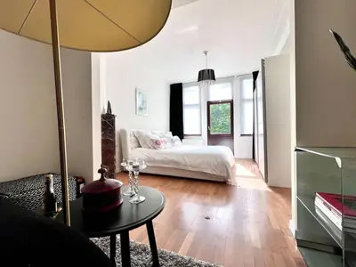 a bedroom with a bed and a table with a lamp at Chic Studio Heart of the City with Balcony in Brussels