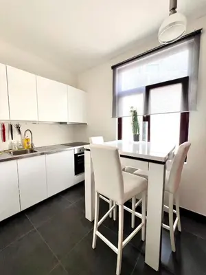 a kitchen with white cabinets and a table and chairs at Chic Studio Heart of the City with Balcony in Brussels