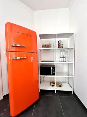 an orange refrigerator in a room with a microwave at Chic Studio Heart of the City with Balcony in Brussels