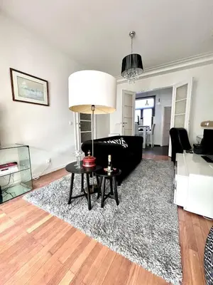 a living room with a black couch and a table at Chic Studio Heart of the City with Balcony in Brussels