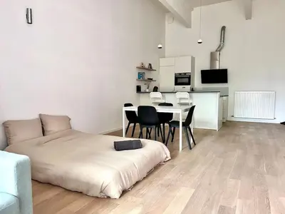 a bedroom with a bed and a table and chairs at Bright Modern Loft in Central Brussels for 4 in Brussels