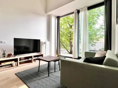 a living room with a couch and a flat screen tv at Bright Modern Loft in Central Brussels for 4 in Brussels