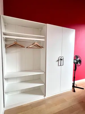 a closet with white shelves and a red wall at Bright Modern Loft in Central Brussels for 4 in Brussels