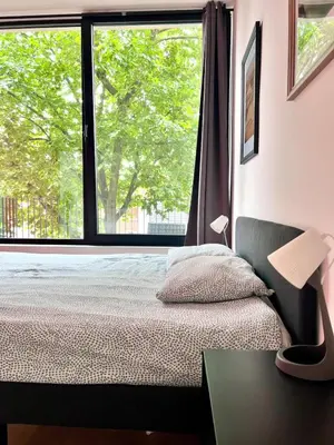 a bedroom with a bed and a large window at Bright Modern Loft in Central Brussels for 4 in Brussels
