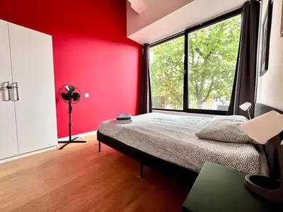 a bedroom with red walls and a bed with a window at Bright Modern Loft in Central Brussels for 4 in Brussels
