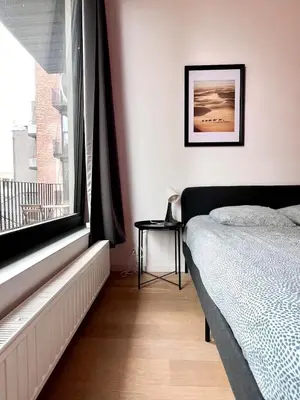a bedroom with a bed and a large window at Bright Modern Loft in Central Brussels for 4 in Brussels