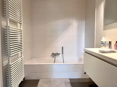 a white bathroom with a tub and a sink at Bright Modern Loft in Central Brussels for 4 in Brussels
