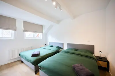 two beds in a bedroom with green sheets at Gallery Louise 2 in Brussels