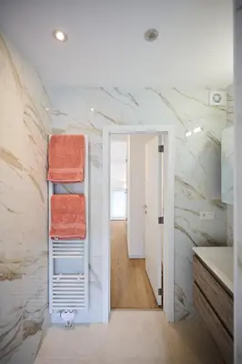 a bathroom with white marble walls and towels on a shelf at Gallery Louise 2 in Brussels