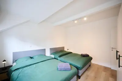 a bedroom with two beds with green sheets at Gallery Louise 2 in Brussels