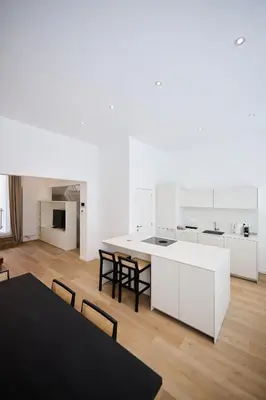 a kitchen with white cabinets and a table and chairs at Gallery Louise 2 in Brussels