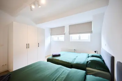a bedroom with two green beds and a window at Gallery Louise 2 in Brussels