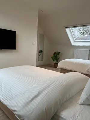 a white bedroom with two beds and a television at FDS Luxe House in Ghent