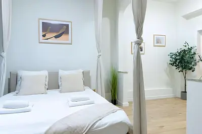 a white bedroom with a bed with white sheets and pillows at Studio idéal pour visiter Bruxelles in Brussels
