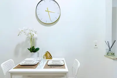 a white table with chairs and a clock on a wall at Studio idéal pour visiter Bruxelles in Brussels