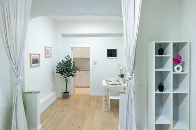 a white living room with a table and a kitchen at Studio idéal pour visiter Bruxelles in Brussels