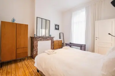 a bedroom with a large white bed and a dresser at New Apartment center of Trendy St Gille in Brussels