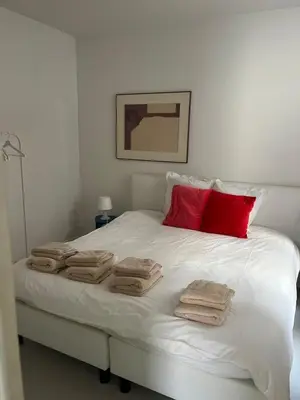 a white bed with towels and red pillows on it at Knus appartement centrum Gent in Ghent