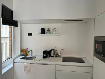 a white kitchen with a sink and a microwave at Knus appartement centrum Gent in Ghent