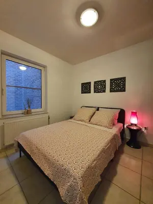 a bedroom with a bed and a window and a lamp at Appartement 2 chambres dans le centre de Vilvoorde in Vilvoorde