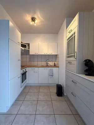 a kitchen with white cabinets and a tile floor at Appartement 2 chambres dans le centre de Vilvoorde in Vilvoorde