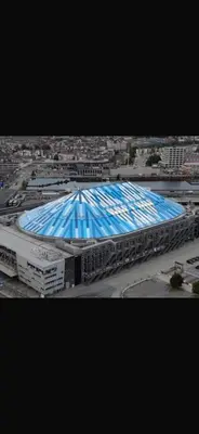 a large stadium with a blue roof in a city at Sportpaleis afasdome in Antwerp