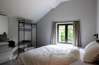 a white bedroom with a bed and a window at Zeer ruime groepswoning voor 24p in Turnhout