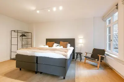 a bedroom with a bed and a chair and a window at Apartment near Antwerp Cathedral in Antwerp