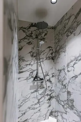 a shower in a bathroom with a marble wall at Apartment near Antwerp Cathedral in Antwerp