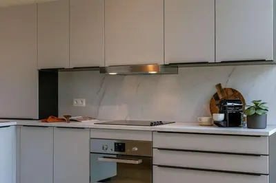 a kitchen with white cabinets and a stove top oven at Modern Suite on Antwerp's Grand Market Square in Antwerp