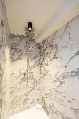 a bathroom with marble walls and a shower at Modern Suite on Antwerp's Grand Market Square in Antwerp
